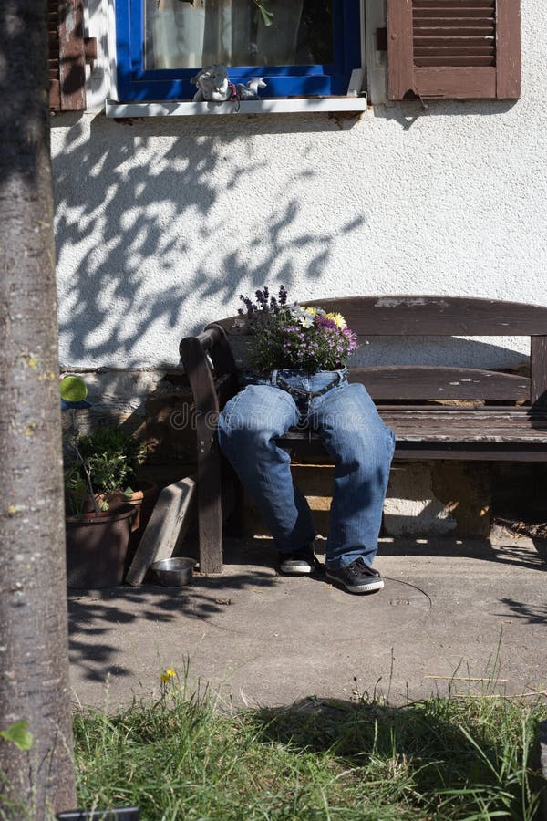 i jeans di taglio decorati con i fiori che si siedono su un giardino bench la a fotografia stock libera da diritti i jeans di taglio decorati con i fiori che si siedono su un giardino bench la a fotografia stock libera da diritti