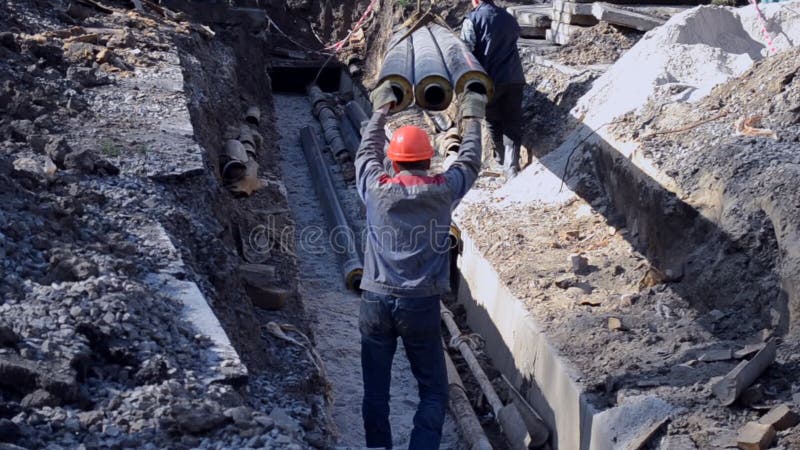 I lavoratori con la gru di costruzione hanno messo le nuove tubature dell'acqua con le lastre di cemento armato