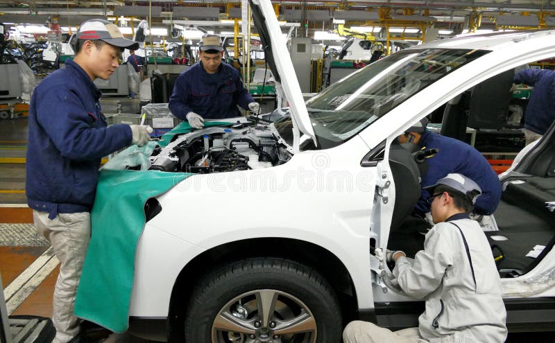 I lavoratori montano un'automobile sulla catena di montaggio nella fabbrica dell'automobile
