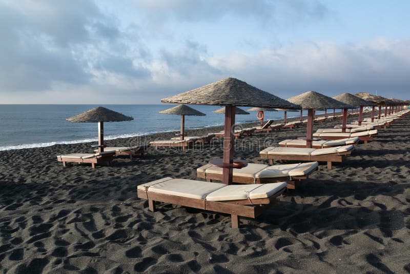 I letti e gli ombrelli d'abbronzatura su Perissa tirano, Santorini, Grecia fotografia stock I letti e gli ombrelli d'abbronzatura su Perissa tirano, Santorini, Grecia fotografia stock