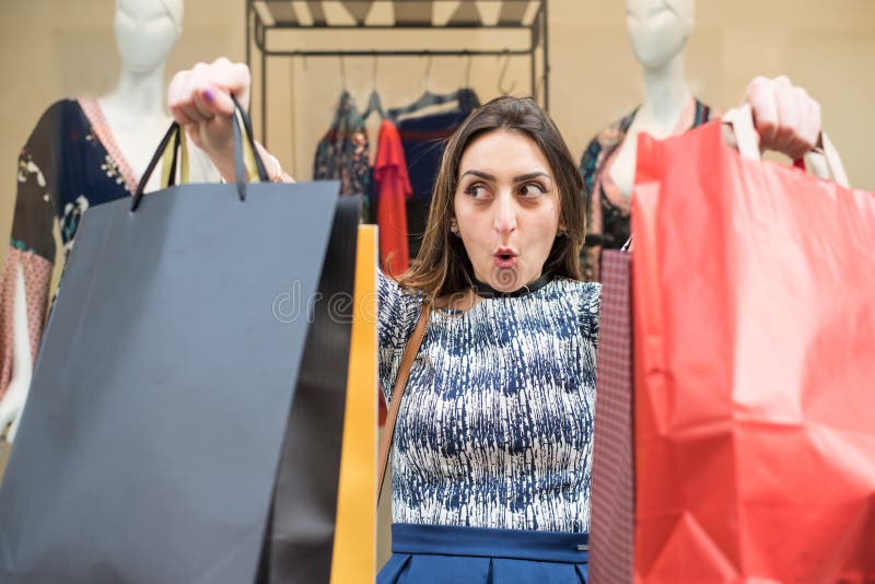 Beautiful brunette girl holding big colorful shopping bags in front of a window of a store in the city mall, Enjoying her day buying new clothes and accessories. Beautiful brunette girl holding big colorful shopping bags in front of a window of a store in the city mall, Enjoying her day buying new clothes and accessories.