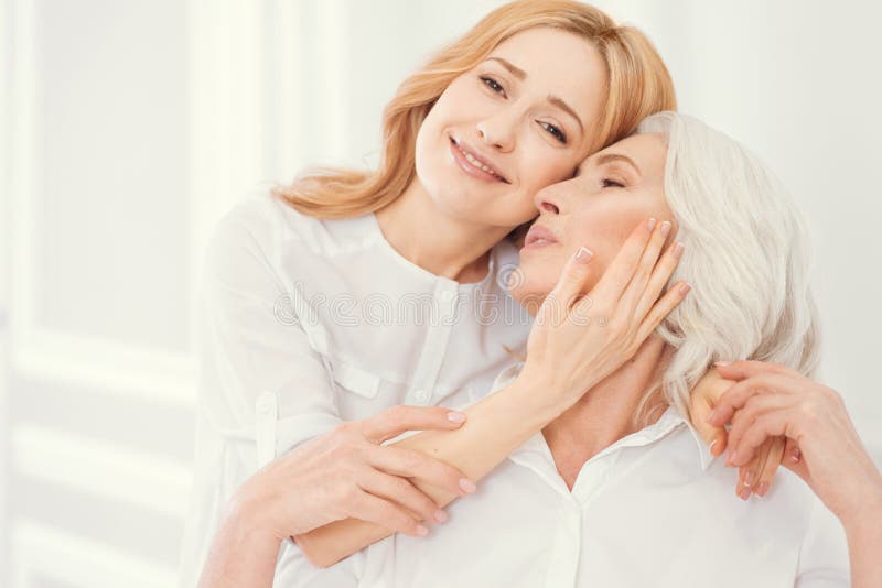 Tender adult daughter embracing her mother with love stock photography Tender adult daughter embracing her mother with love stock photography