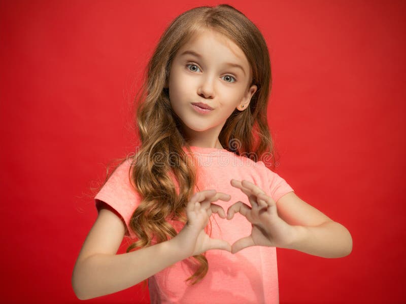 The happy teen girl standing and smiling against red background.