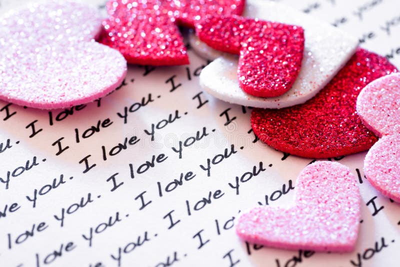 The words ' I Love You' typed many times on paper and glittery hearts scattered around. The words ' I Love You' typed many times on paper and glittery hearts scattered around