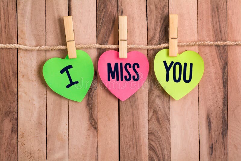 I miss you text in color heart shaped note with clothespin and rope on wooden background. I miss you text in color heart shaped note with clothespin and rope on wooden background