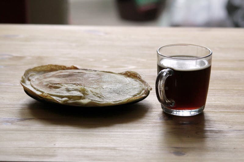 I morgonen på tabellen en kopp kaffe och en platta av pannkakor royaltyfri foto I morgonen på tabellen en kopp kaffe och en platta av pannkakor royaltyfri foto