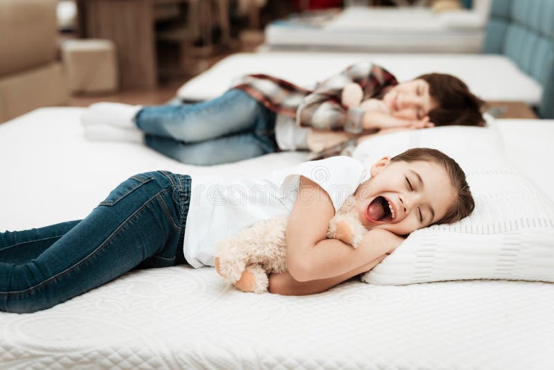 I piccoli abbracci felici della ragazza sopportano trovarsi sul letto Nei sonni del ragazzino del fondo fotografie stock libere da diritti
