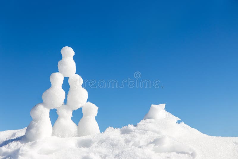I piccoli pupazzi di neve calcola la costruzione della piramide nella neve immagine stock I piccoli pupazzi di neve calcola la costruzione della piramide nella neve immagine stock