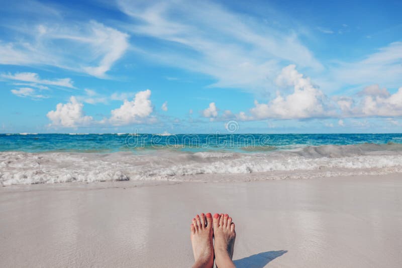 I piedi della donna sulla spiaggia caraibica tropicale Oceano e cielo blu