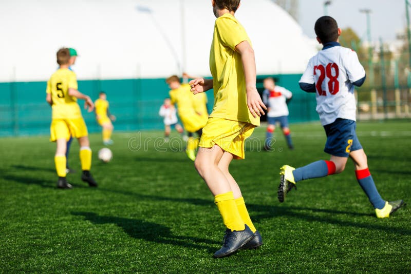 I ragazzi delle squadre di football americano in abiti sportivi bianchi gialli giocano a calcio sul campo verde abilit? di goccio fotografia stock libera da diritti