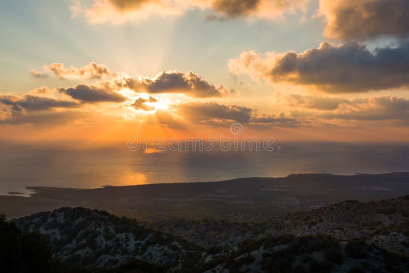 I raggi di sole del sole di sera dietro le nuvole alla costa HDR del Cipro abbelliscono