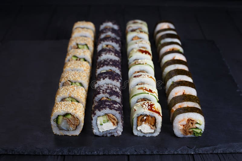 I rotoli di sushi tradizionali giapponesi hanno messo con i materiali da otturazione affumicati dell'anguilla sopra fotografia stock I rotoli di sushi tradizionali giapponesi hanno messo con i materiali da otturazione affumicati dell'anguilla sopra fotografia stock