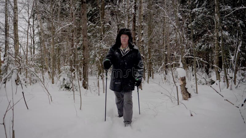 I rörelsemannen som fotvandrar till och med den snöig Forest With Trekking Poles In vintern