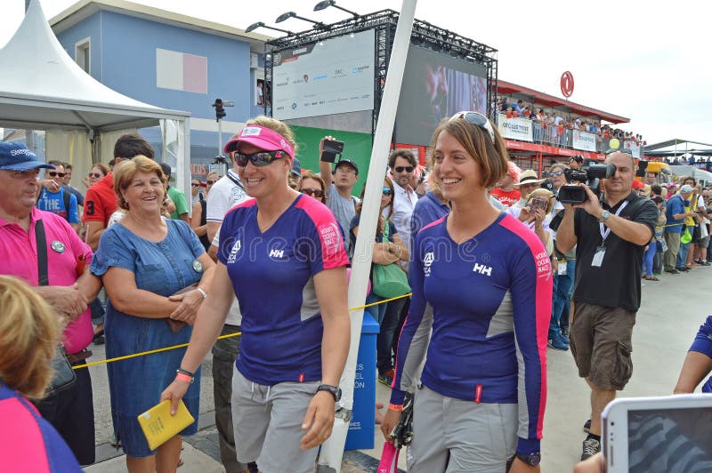 I sorrisi come FECCIE del gruppo si accinge all'attrezzatura la corsa di yacht più dura dei mondi. Gli alti alcoolici come tutto il gruppo femminile cammina al loro yacht di corsa per iniziare la corsa dell'oceano di Volvo