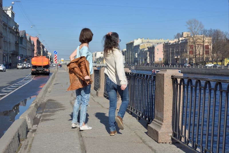 I turisti delle giovani signore in San Pietroburgo Russia si divertono insieme un giorno soleggiato, si spogliano e saltano della immagini stock libere da diritti I turisti delle giovani signore in San Pietroburgo Russia si divertono insieme un giorno soleggiato, si spogliano e saltano della immagini stock libere da diritti