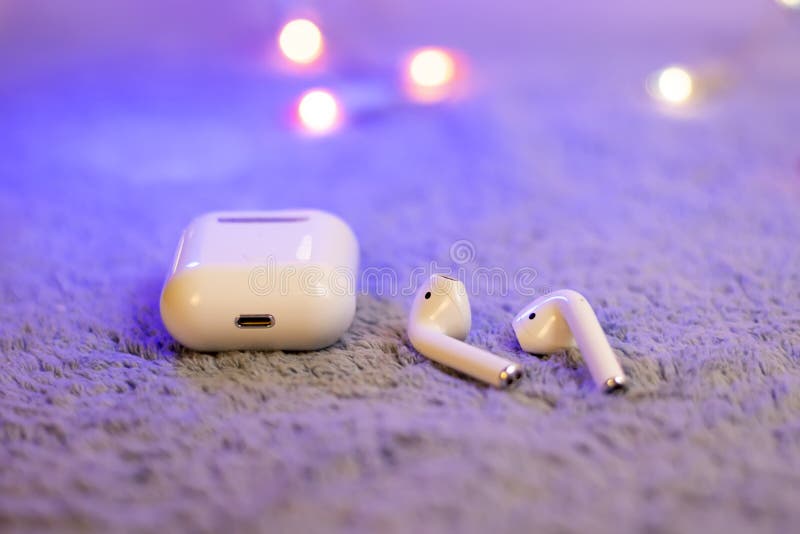I12 tws Wireless white headphones on gray plush stock image.