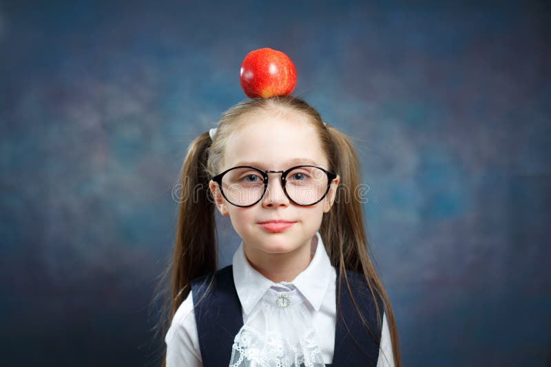 I vetri svegli di usura della scolara tengono Apple sulla testa fotografia stock I vetri svegli di usura della scolara tengono Apple sulla testa fotografia stock