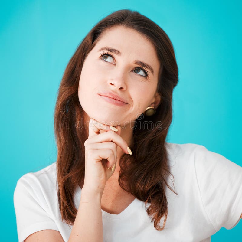 I wonder... Studio shot of an attractive young woman looking thoughtful against a blue background.