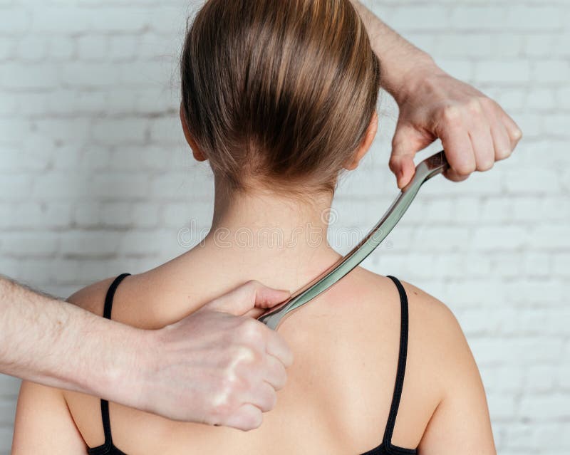 IASTM treatment, girl receiving soft tissue treatment on her neck with stainless steel tool stock images