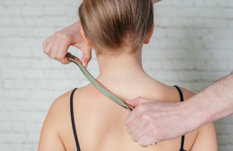 A girl receiving soft tissue treatment on her neck with IASTM stainless steel tool royalty free stock photo