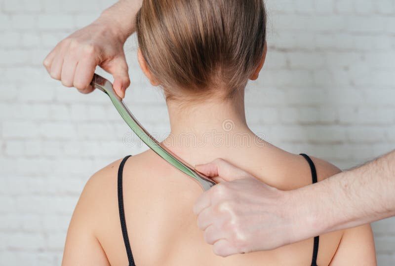 IASTM treatment, girl receiving soft tissue treatment on her neck with stainless steel tool royalty free stock photos