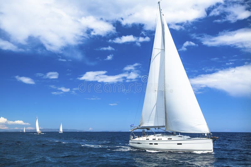 Iate do barco de navigação ou raça da regata da vela no mar da água azul esporte