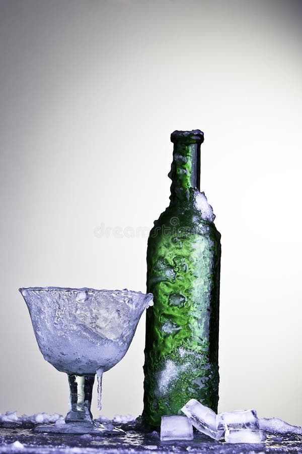 Frozen bottle and glass with ice cubes cold drink background with nice gradient and copy space alcohol wine. Frozen bottle and glass with ice cubes cold drink background with nice gradient and copy space alcohol wine