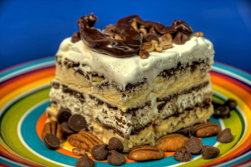 This is a picture of ice cream sandwiches pilled on top of each other, with some nuts and cream. This is a picture of ice cream sandwiches pilled on top of each other, with some nuts and cream