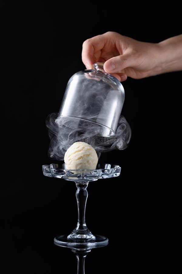 Ice cream ball on the glass cake stand and steam under glass dome