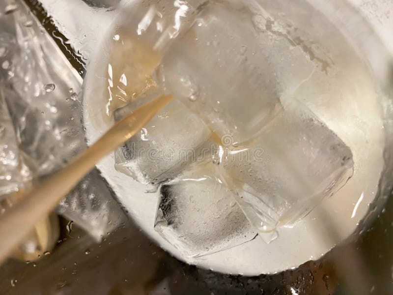 Ice Cube in a White Glass, Sprinkled with Grapefruit Juice, Isolated on