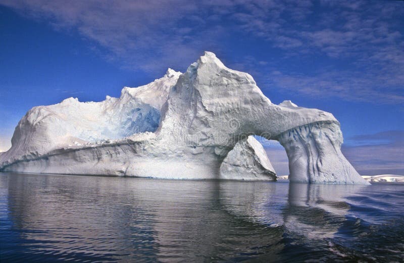 Iceberg con un arco naturale, riflesso nell'acqua, ancora, tranquilla bellezza dell'Antartide, in fondo il mondo.
