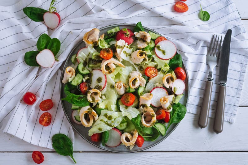 Icebersallad med hönsfilérullar, tunt skivad rädisa, gurkor, spenatblad, körsbärstomater royaltyfri foto Icebersallad med hönsfilérullar, tunt skivad rädisa, gurkor, spenatblad, körsbärstomater royaltyfri foto