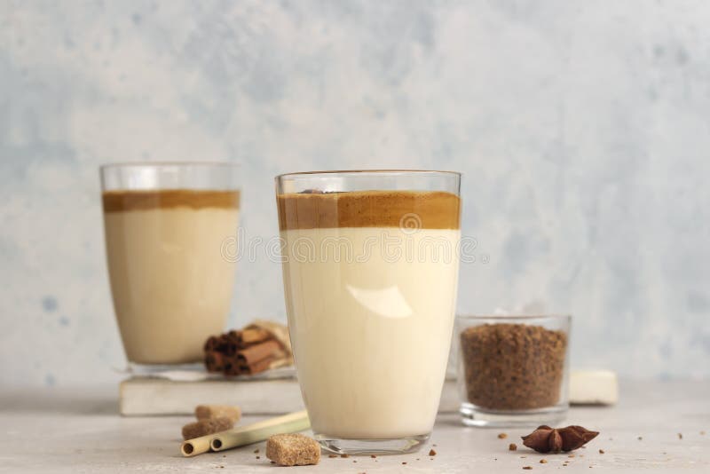 Iced Dalgona coffee in tall glass with spices. A trendy fluffy creamy whipped coffee. Korean coffee drink.