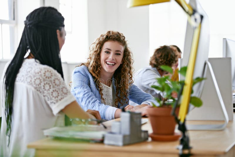 Ich liebe es, hier zu arbeiten. zwei Designer, die sich während der Zusammenarbeit an einem Computer unterhalten. stockfoto