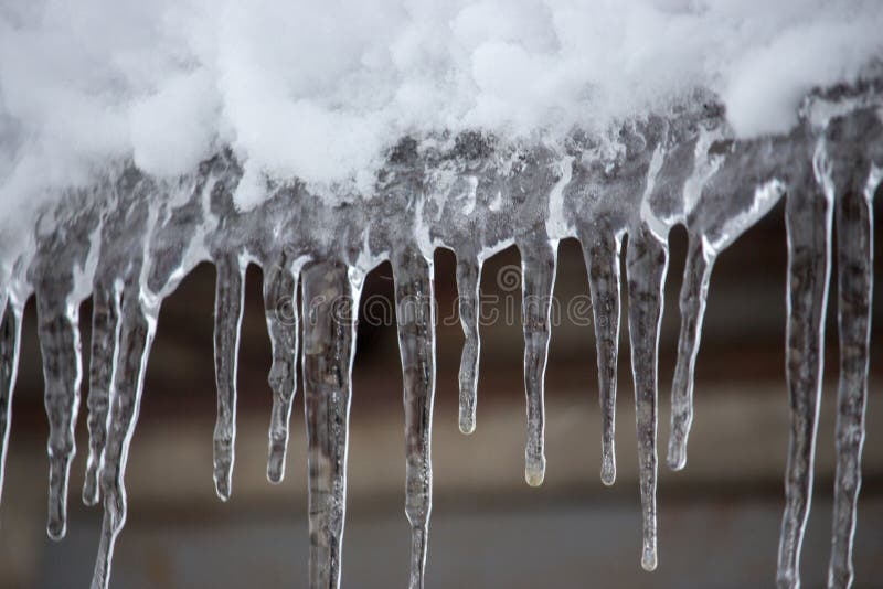 Icicles and snow on roof closeup. Winter weather concept. Froze and ice background. Snow and icicle. Melting icicles.