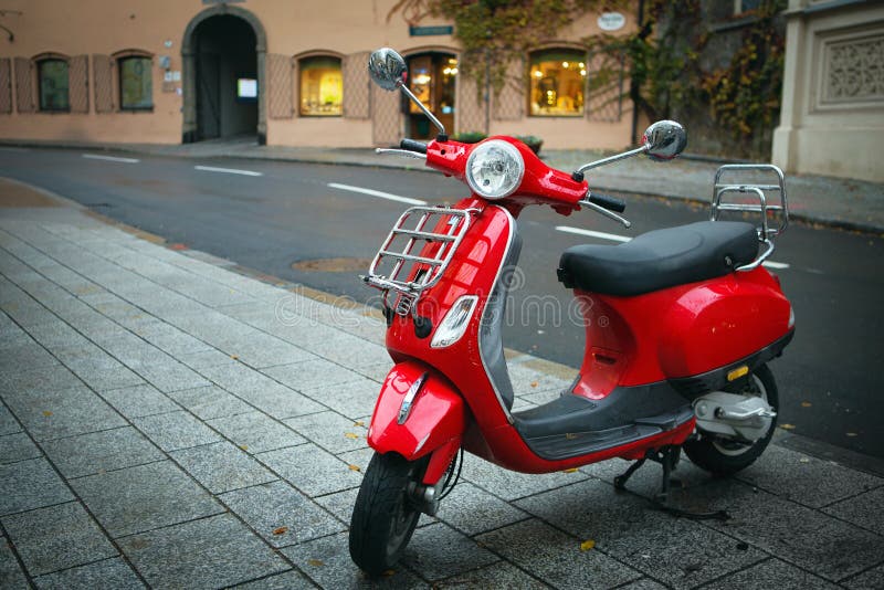 Iconische rode Vespa, ouderwetse Italiaanse motorfiets, wordt geparkeerd op de straatstoep in het centrum van Salzburg stock foto Iconische rode Vespa, ouderwetse Italiaanse motorfiets, wordt geparkeerd op de straatstoep in het centrum van Salzburg stock foto