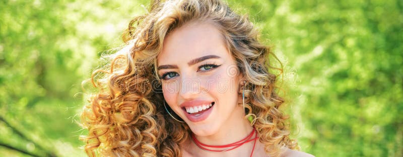 Idealne włosy kręcone. długie włosy kędzierzawe blond. idealna kobieta uśmiechająca się na wiosennym tle. piękno i doskonałe zdrow zdjęcia royalty free