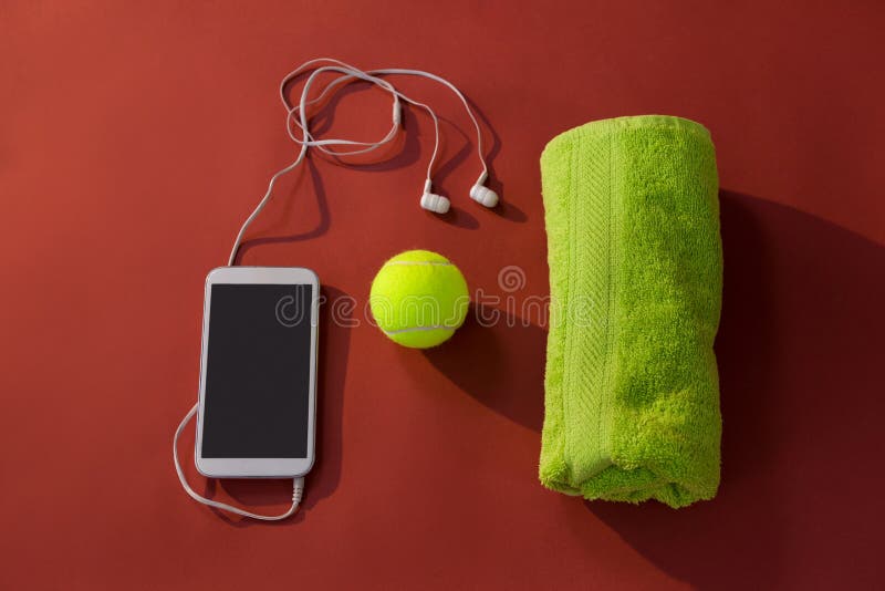 Ideia aérea da bola de tênis entre o guardanapo e do telefone celular com fones de ouvido da em-orelha fotos de stock royalty free Ideia aérea da bola de tênis entre o guardanapo e do telefone celular com fones de ouvido da em-orelha fotos de stock royalty free