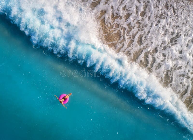 Ideia aérea da natação da jovem mulher no anel cor-de-rosa da nadada