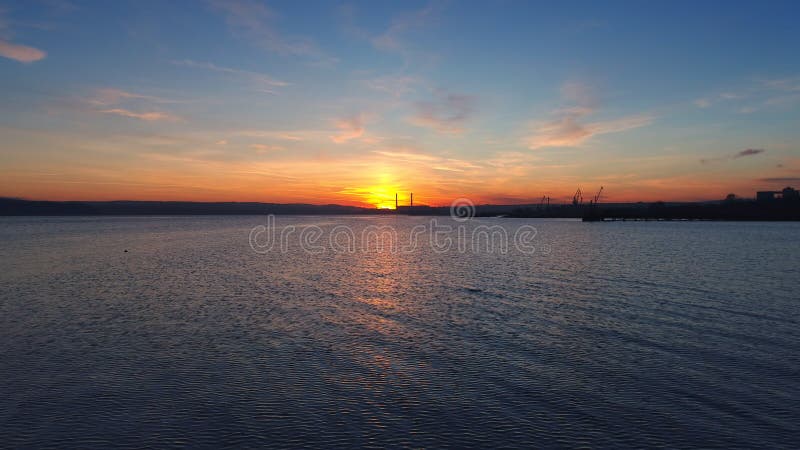 A ideia aérea do nascer do sol dourado sobre a água do mar e a ondinha acena