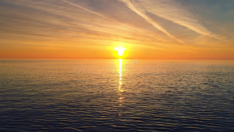 A ideia aérea do nascer do sol dourado sobre a água do mar e a ondinha acena