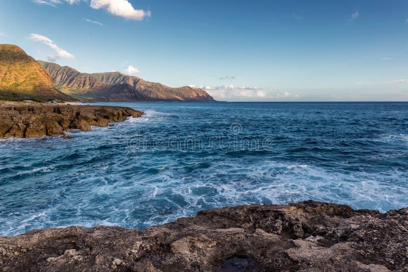 Ideia do litoral rochoso na luz solar morna da noite, ilha de Oahu foto de stock Ideia do litoral rochoso na luz solar morna da noite, ilha de Oahu foto de stock