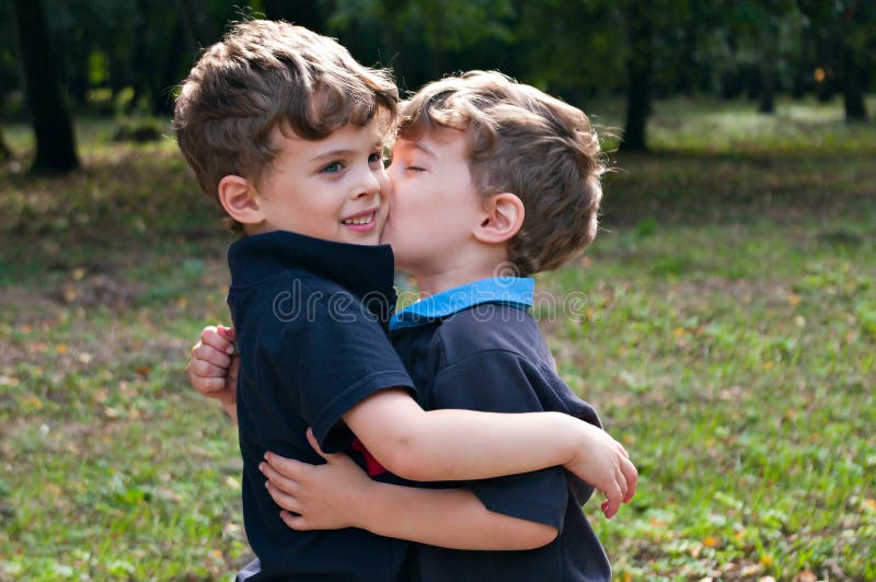 Identical twin brothers embraced each other with a kiss. 