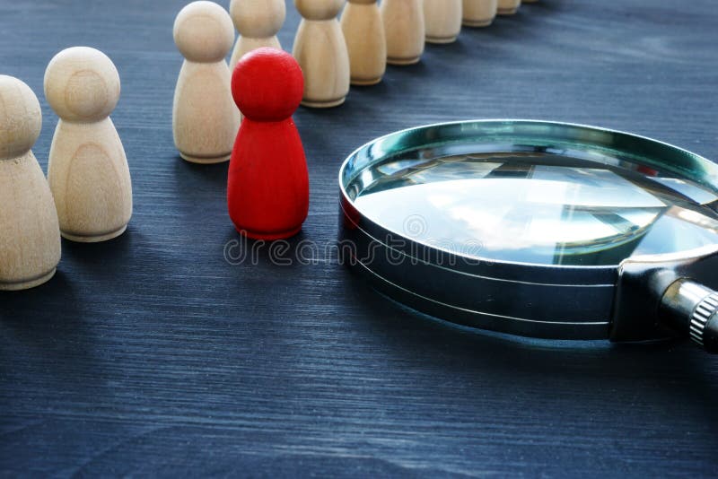 Identify concept. Recruitment and talent management. Red figurine and magnifying glass. Identify concept. Recruitment and talent management. Red figurine and magnifying glass.
