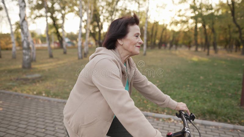 Idosa andando de bicicleta no parque vídeos de arquivo