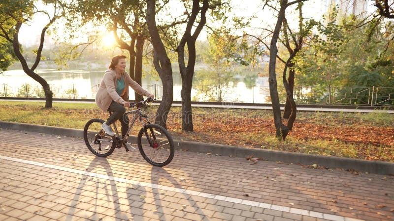 Idosa andando de bicicleta no parque público video estoque