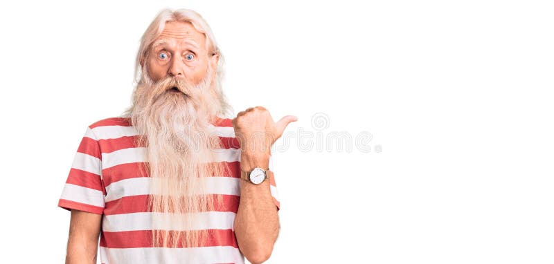 Old senior man with grey hair and long beard wearing striped tshirt surprised pointing with hand finger to the side, open mouth amazed expression. Old senior man with grey hair and long beard wearing striped tshirt surprised pointing with hand finger to the side, open mouth amazed expression