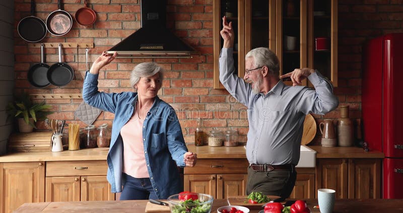Idosos felizes e ativos cônjuges dançando na cozinha