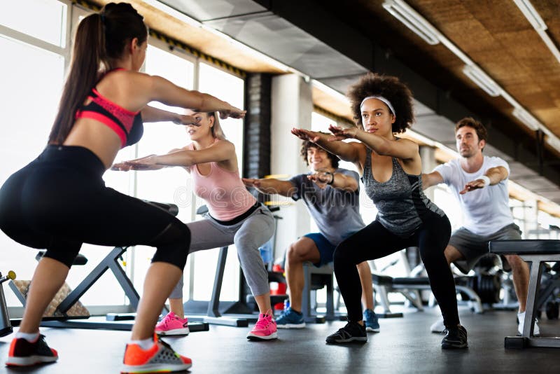 Idrott och livsstilskoncept. grupp av leende personer som tränar tillsammans på gym arkivfoto