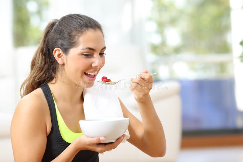 Sportswoman eating cereals after sport sitting on the floor at home. Sportswoman eating cereals after sport sitting on the floor at home